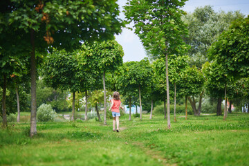 Naklejka premium Adorable preschooler girl having fun in a green park on a summer day.