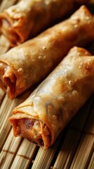 Detailed close-up top view photograph of crispy spring rolls with a golden-brown wrapper on a bamboo mat showcasing texture and filling
