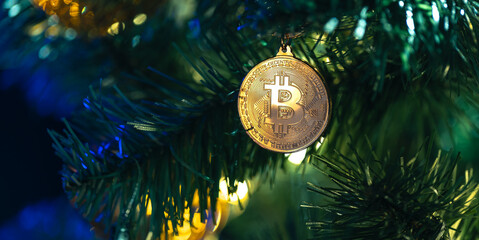 Bitcoin coin on christmas tree with bokeh lights. Finance concept.