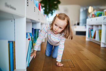 Five year old girl selecting a book in municipal library