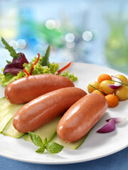 Boiled sausages in white plate with salad on blurred background