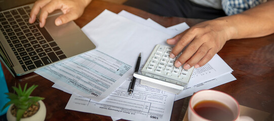 Budget and Tax planning concept. Acountant hand using calculator and review tax form. Represents personal finance, tax preparation, and budgeting, season to pay tax-banner image.