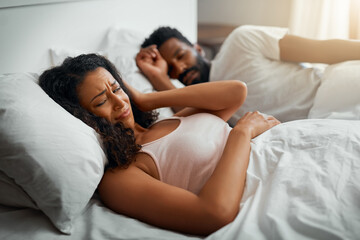 Couple, sleep and home in bedroom with annoyed, discomfort and snoring as romantic partner. Woman, man and unhappy with insomnia, irritated and fatigue as frustrated in morning, rest and relationship