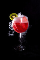 Refreshing cocktail of watermelon chunks with kiwi slice and dry ice vapor on dark background