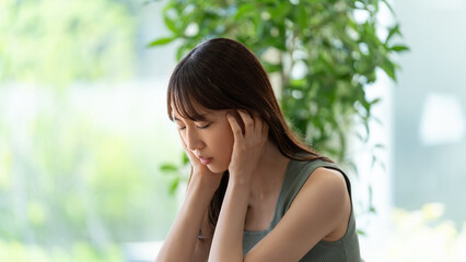 頭を押さえて悩む若い女性