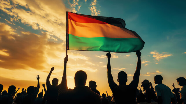Silhouetted crowd cheering and waving comoros flag at sunset