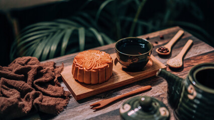 Chinese traditional festival mid-autumn baked mooncake and teacup on a wooden plate for menu...