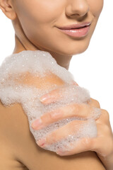 Fototapeta premium Young beautiful woman washing her shoulders with soap foam.
