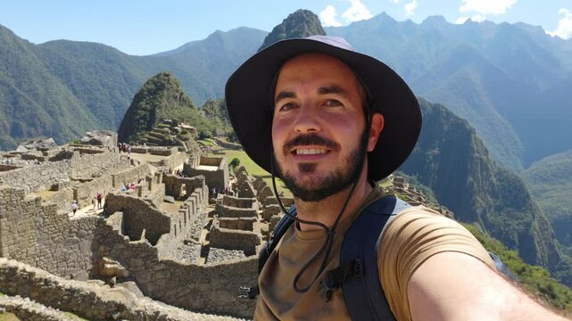 POV video selfie of happy young adult man enjoying Machu Picchu landscape. Joyful traveler enjoying vacation visiting Peru. South american travel holidays concept.