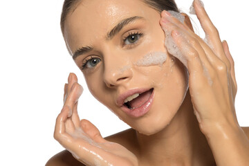 Naklejka premium Young beautiful happy woman washing her face in soap foam.