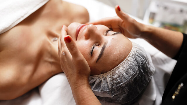 Close-up of a young woman receiving a soothing facial massage at a beauty spa. The scene highlights the luxurious spa experience and emphasizes the benefits of professional skin and body care.