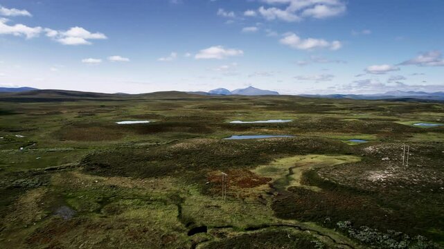 Flying over the serene beauty of Flatruet heathland tundra and its tranquil ponds in J&auml;mtland Sweden, with majestic mountains of nature reserve Skardsfjella og Hyllingsdale Norway in the background