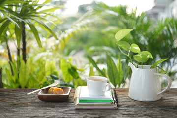coffee cup and notebook with dessert and plant pot at balcony outdoor