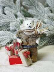 Christmas character polar bear in a sweater with presents in his hands on the background of pine branches