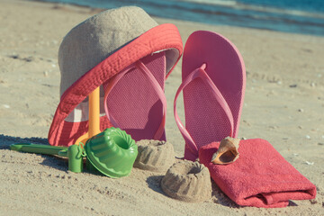 Different shapes made of sand, children toys for playing and accessories for relax on beach. Summer time
