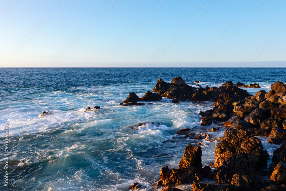 Wall mural ocean rocks are scattered along the shoreline. rugged rocks surrounded by deep blue water and gentle