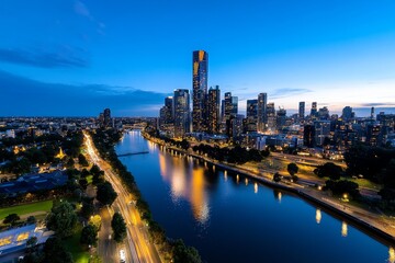 Fototapeta premium Aerial timelapse of Melbourne at night, showcasing the cityâ€™s skyline and the Yarra River illuminated by city lights