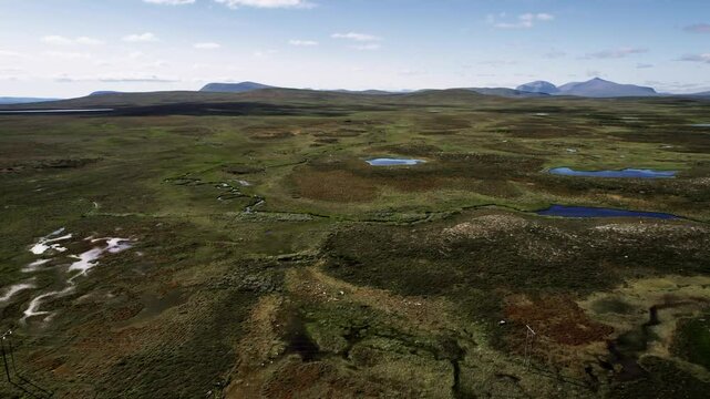 Experience the breathtaking views of moors, ponds, and the Norwegian mountains of Skarsfjella as a drone ascends over the Flatruet High Fell heathlands in Sweden