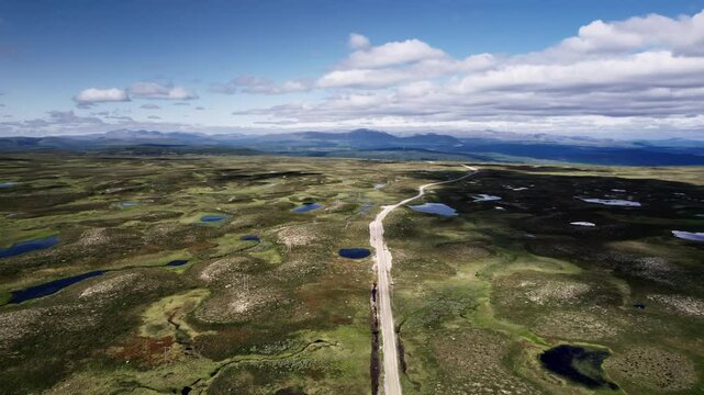 Flying over the country road on Flatruet Fell in J&auml;mtland, H&auml;rjedalen Sweden, showcased by lush moorland and the majestic V&aring;l&aring;dalen Nature Reserve mountains