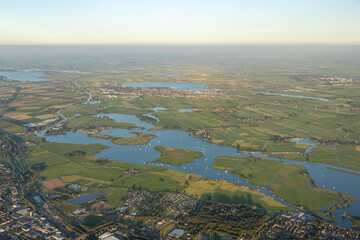 aerial image of a lake, Alkmaarder meer, in the Netherlands during summer with many sailboats sailing around island during race, regatta, match in soft early evening light