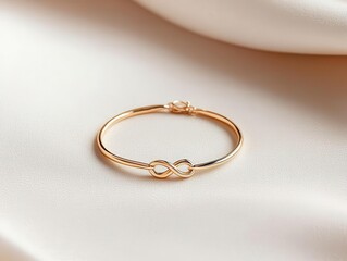 Thin gold bracelet with abstract shape accents, laid on a smooth white surface, modern and chic