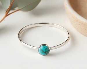 Thin silver bracelet with single turquoise stone, displayed on clean white surface, modern boho style