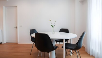 A clean, minimalist dining area with a white dining table, black dining chairs. 