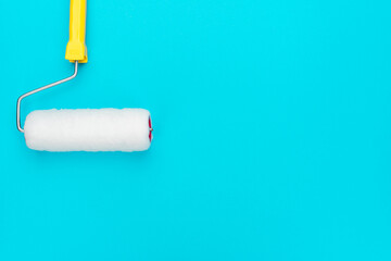 Clean paint roller on the turquoise blue background with copy space. Home renovation concept.