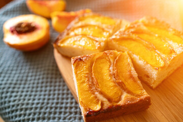 A dessert made of sliced peaches is on a wooden cutting board. The dessert is covered in sugar and looks delicious.