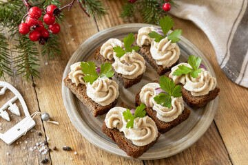 Christmas appetizer New year meal idea. Creative appetizer christmas. Creamy pate sandwiches of herring on a rye bread on the rustic table.