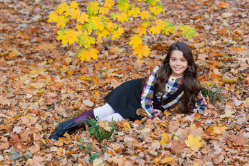 Stylish teen girl at school break. Back to school. Autumn leaves. Girl in fall park wear uniform....