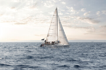 Serene sailboat cruising on calm sea waters with a soft glow of sunset