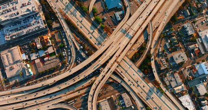 Hundreds of cars moving by the roads of a huge interchange. Aerial perspective on the traffic system of Los Angeles, California, US.