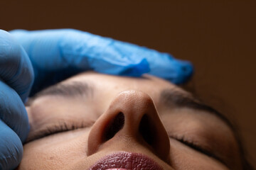 Beautician wearing blue gloves preparing woman for cosmetic procedure