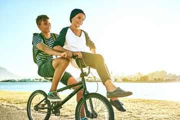 Happy boys, bicycle and riding with friends in nature for commute, travel or outdoor adventure. Male person, teenagers and students cycling back home on bike, road or street by lake, water or river