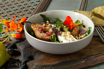 bowl of salad with baked pear, arugula and feta on wooden table