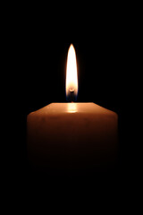 Close-up of a lit candle in total darkness.