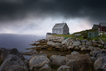 House on the coast in Nova Scotia overlooking the water as dark storm clouds approach from the sea © Madhavan