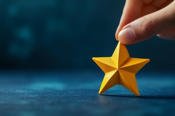 Fototapeta premium A close-up of a hand holding a yellow star-shaped object against a blurred blue background, emphasizing its geometric design and bright color