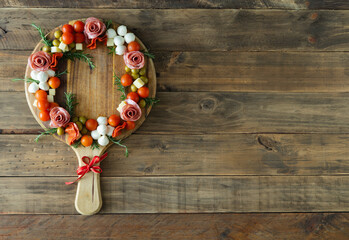 Wooden board with a round shape and food around it forming a crown. Space for copy.