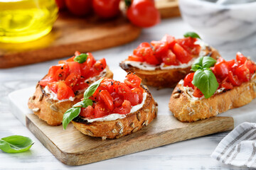 Cherry tomatoes and cream cheese bruschettas with fresh basil leaves.