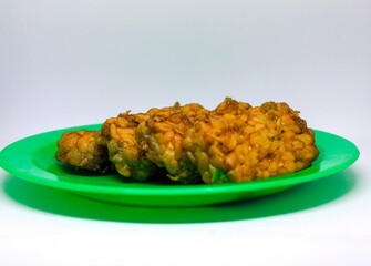 Fried tempeh food is served on a small green plate with a white background