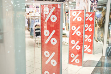 Red discount percentage signs in modern shopping mall highlighting seasonal sales opportunities.