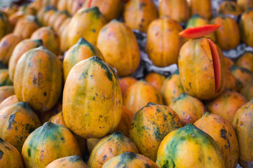 Close-up photo of fresh yellow and green papayas in indian vegetable market.