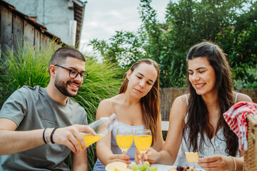 Group of three friends or family having picnic in backyard or garden