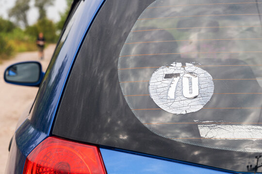 Old worn out sticker 70 on the rear window of a car