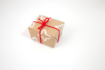  Brown paper wrapped gift with white patterns made by folded toilet paper roll, tied with red ribbon. Unique textured design for personalized, creative, and festive gift giving