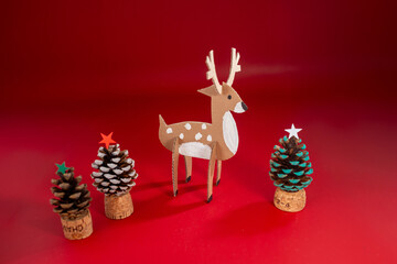 Festive holiday display, pine cone Christmas trees with decorations, red star, colorful ornaments, handmade paper reindeer figurine craft, recycled material concept