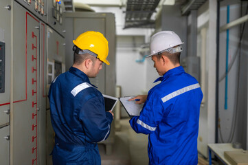 Electrical engineers and technicians work together to solve electrical system failures in industrial control rooms.supervisor maintains the circuit cabinet.