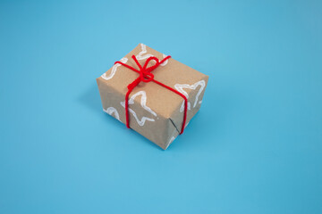 Brown paper gift adorned with white star pattern from folded toilet paper roll, finished with bright red ribbon. Creative wrapping technique using everyday items for a festive look